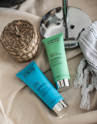ANNEMARIE BÖRLIND Sensitive Cream Mask und Hydro Boost Mask auf hellem Stoff neben Korb und Spiegel