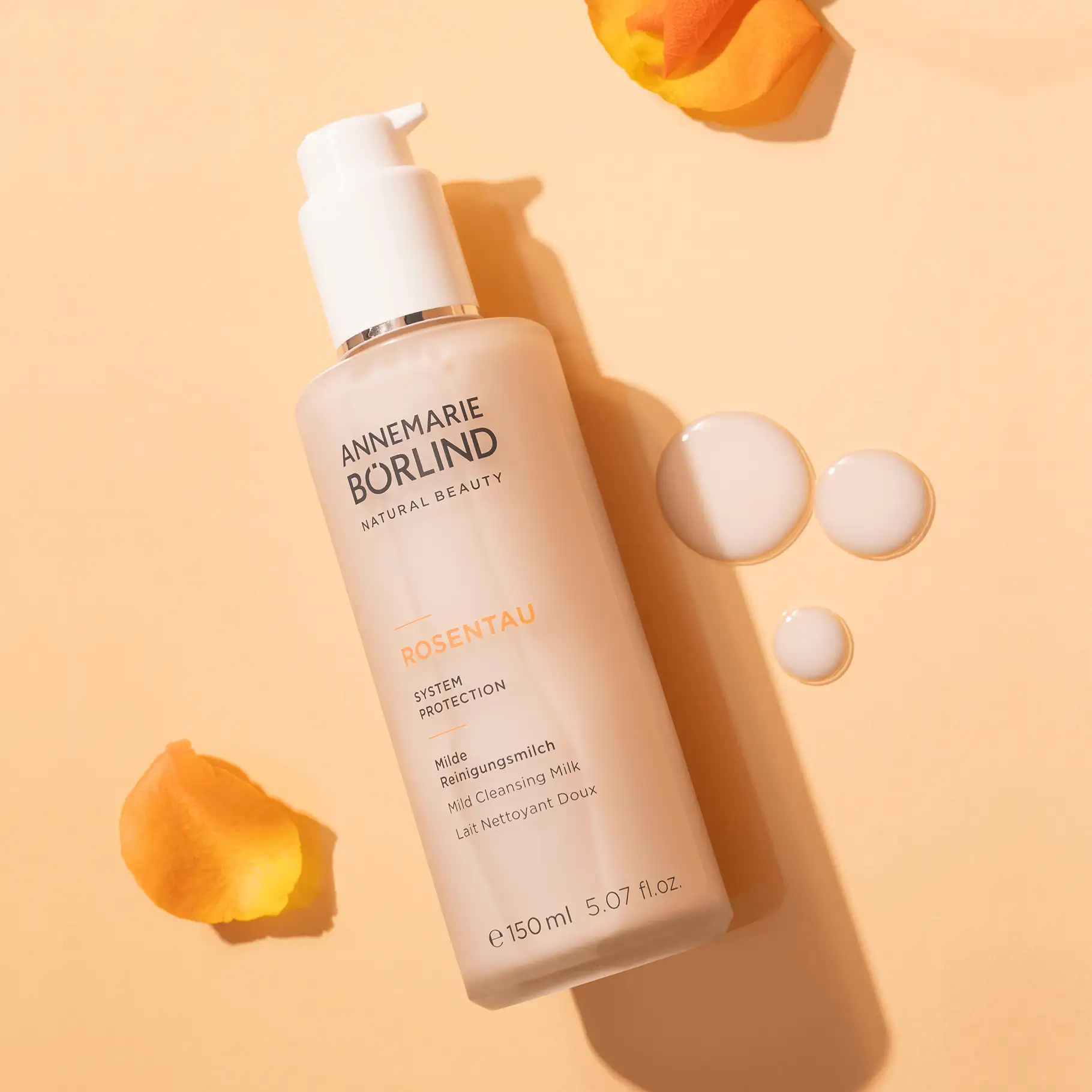 ANNEMARIE BÖRLIND ROSENTAU milde Reinigungsmilch im Spender mit Rosenblüten auf beigem Hintergrund