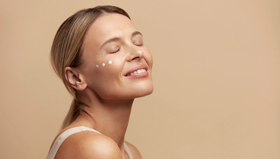 Smiling woman with natural, glowing skin and eye-cream dots—ideal for the best skincare routine for women over 40