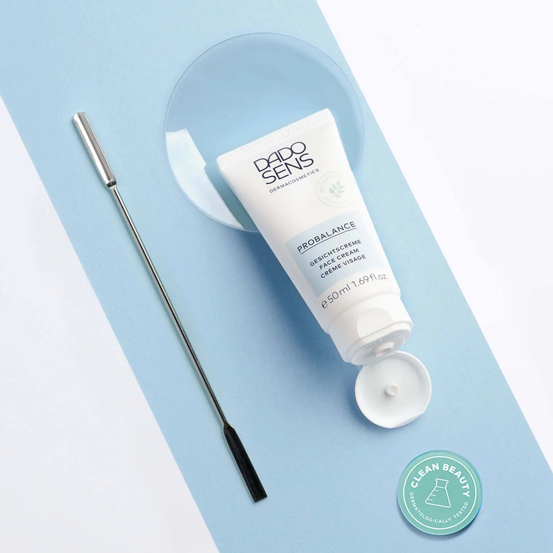 DADO SENS PROBALANCE Gesichtscreme 50 ml mit offenem Deckel, Spatel und Clean Beauty Siegel auf blauem Hintergrund