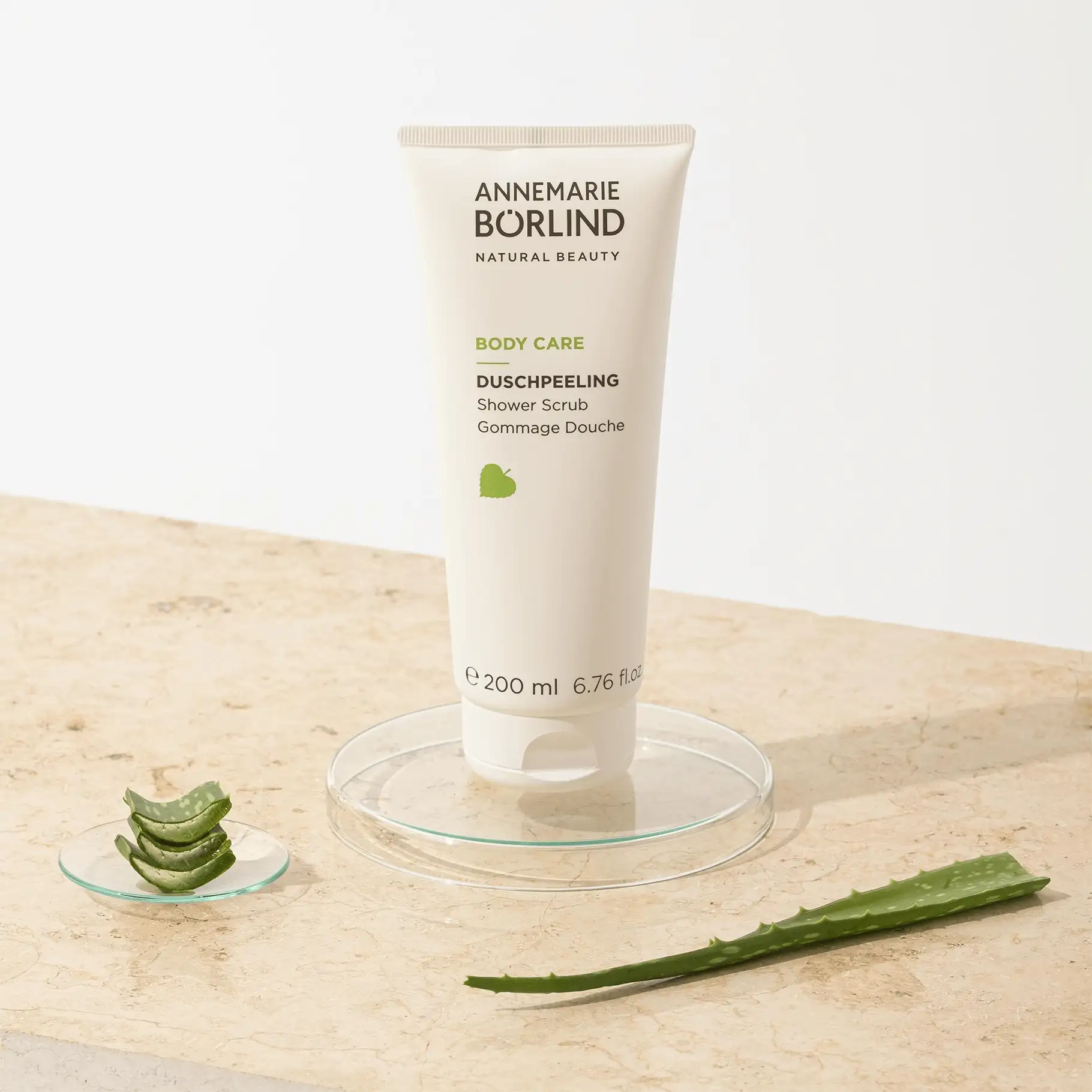 ANNEMARIE BÖRLIND Body Care Duschpeeling 200 ml mit Aloe-Vera-Blatt und -Stücken auf Marmorplatte