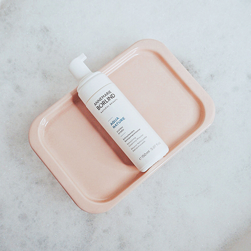 ANNEMARIE BÖRLIND AQUA NATURE Reinigungsmousse auf rechteckigem, rosafarbenem Tablett vor hellem Hintergrund