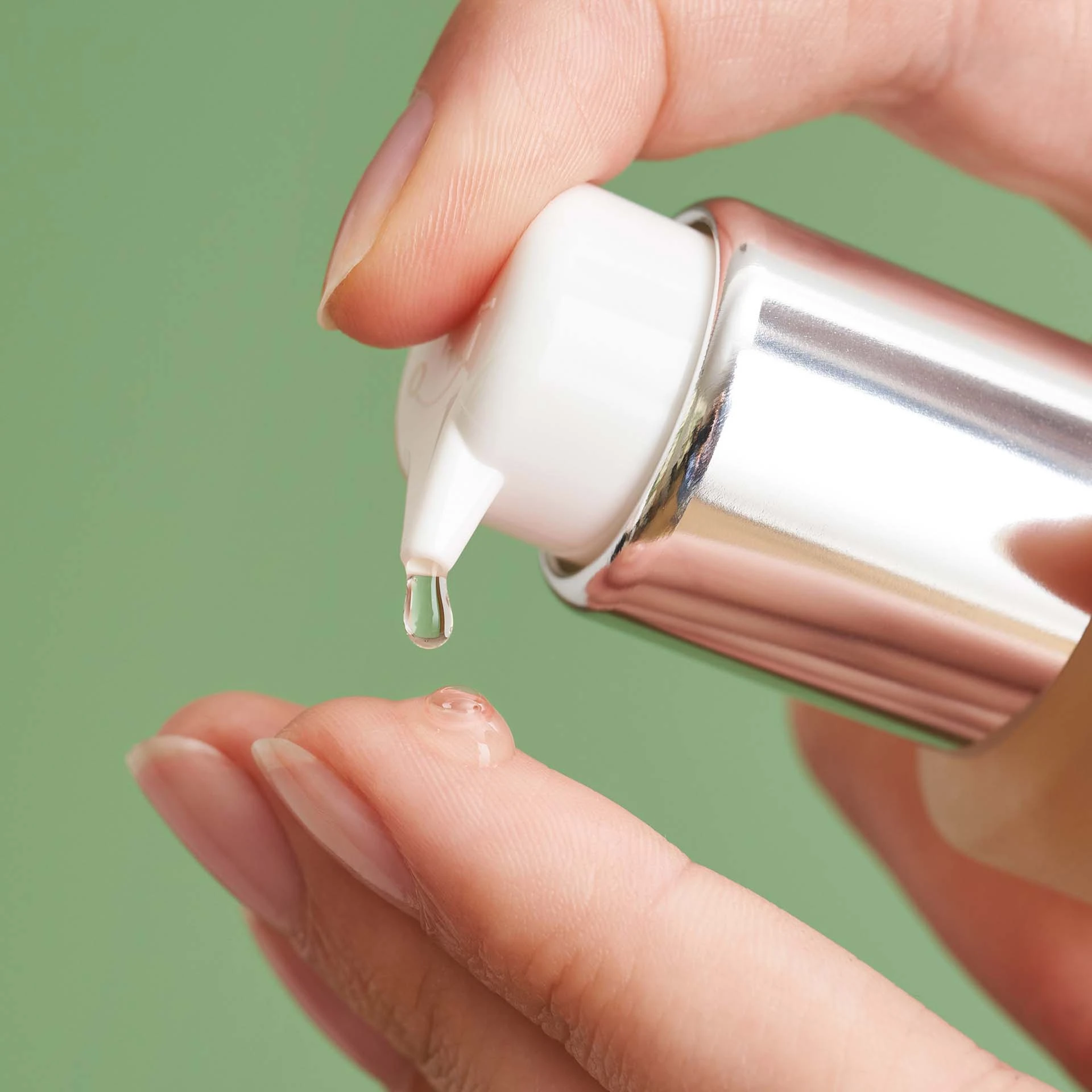 DADO SENS SENSACEA Intensivserum wird als klare Flüssigkeit aus silbernem Spender auf Finger getropft