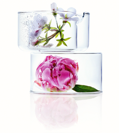 Zwei stapelbare Glasgefäße, oben mit weißen Blüten und unten mit einer pinken Pfingstrose, vor weißem Hintergrund