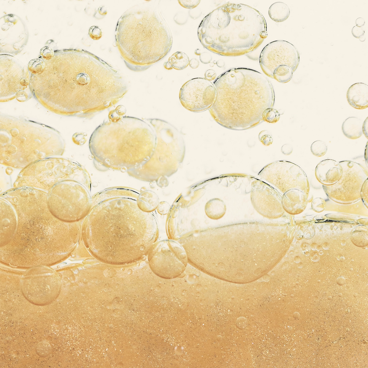 Nahaufnahme von goldfarbenen Bläschen in einer klaren Flüssigkeit, die eine zweiphasige Textur zeigen
