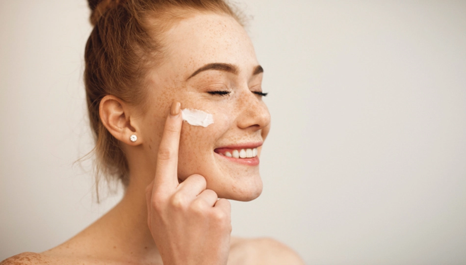 Smiling woman applying face cream – skincare routine for days when your skin is not cooperating