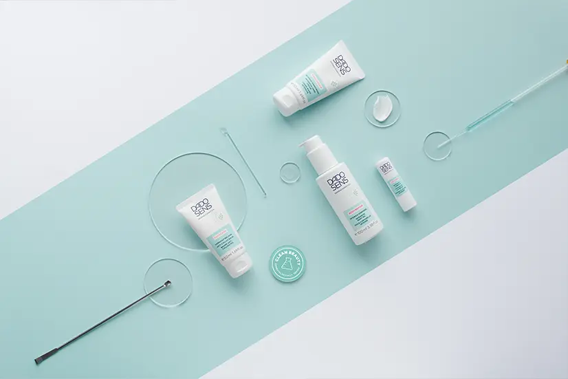 DADO SENS Spezialpflege mit Creme, Lotion, Lippenpflege und Laborausrüstung auf blau-weißem Hintergrund