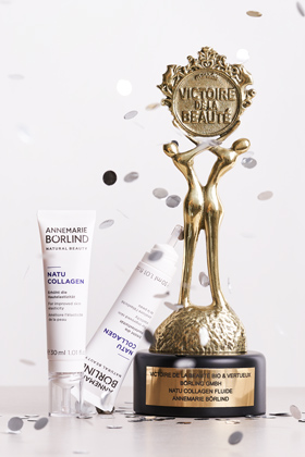 ANNEMARIE BÖRLIND Natu Collagen Fluid neben goldener Victoire de la Beauté Trophäe mit Konfetti
